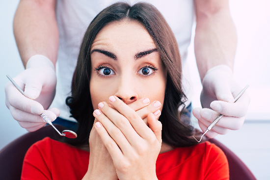 anxious woman covering her mouth before a procedure, would benefit from oral sedation