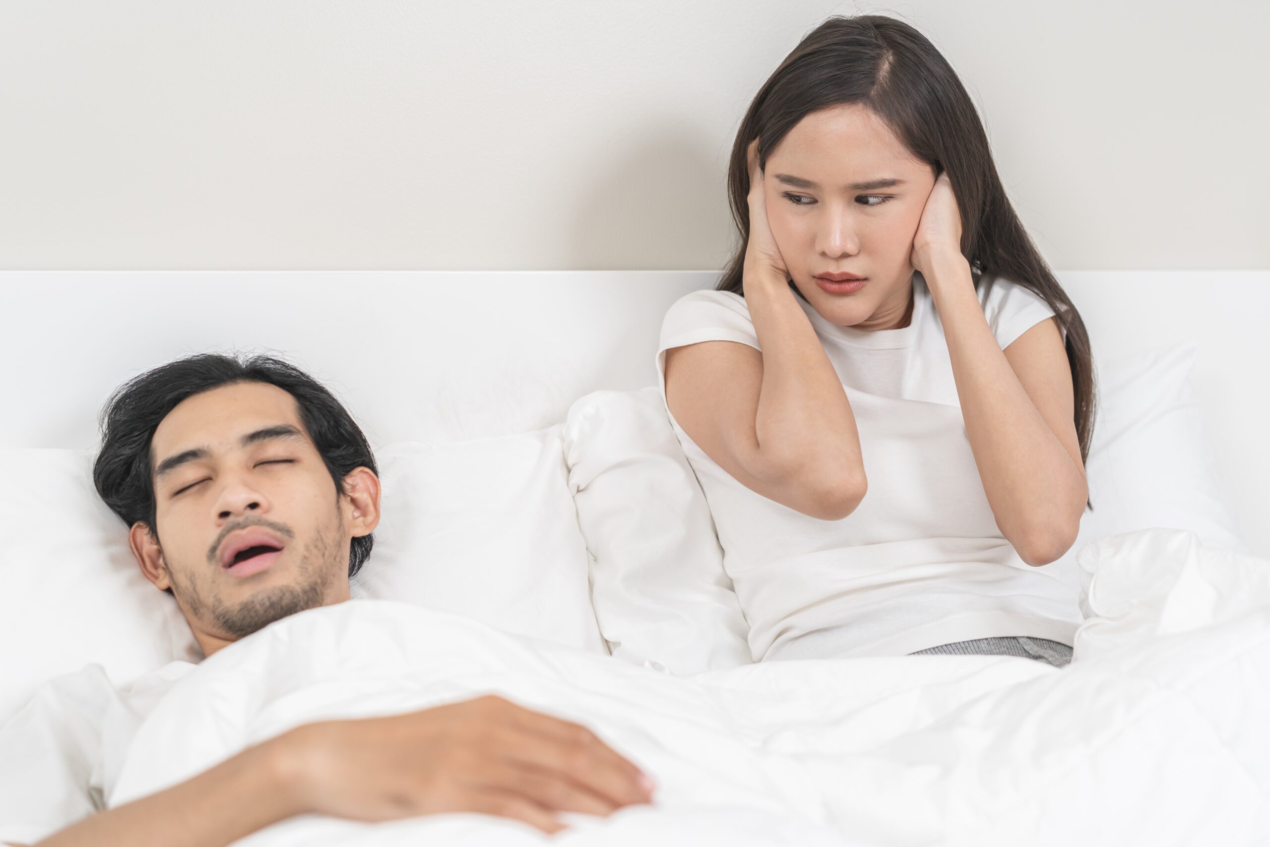 young man suffering from sleep disorder and disturbing his partner