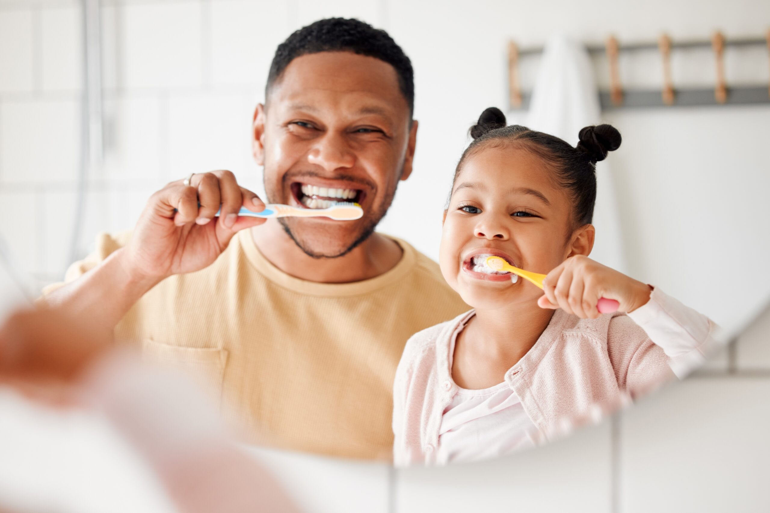 father and daughter brushing their teeth, practicing proactive dental care